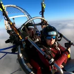 Pasajera feliz en un vuelo en paramotor sobre un mar de nubes simbolizando el mejor paramotor precio para una experiencia biplaza.