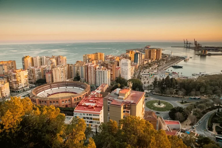 Panorámica de la plaza de toros y el puerto al atardecer, una de las mejores actividades en Málaga para disfrutar.