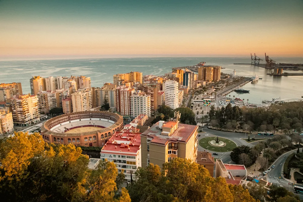 Panorámica de la plaza de toros y el puerto al atardecer, una de las mejores actividades en Málaga para disfrutar.