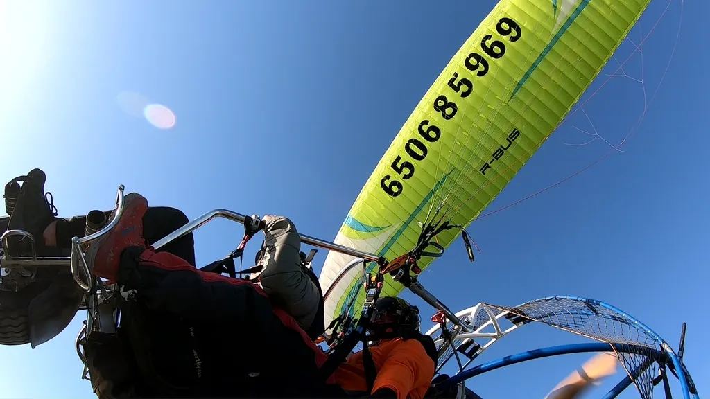 Vista desde abajo del ala de un paramotor en pleno vuelo con un número para preguntar por el paramotor precio