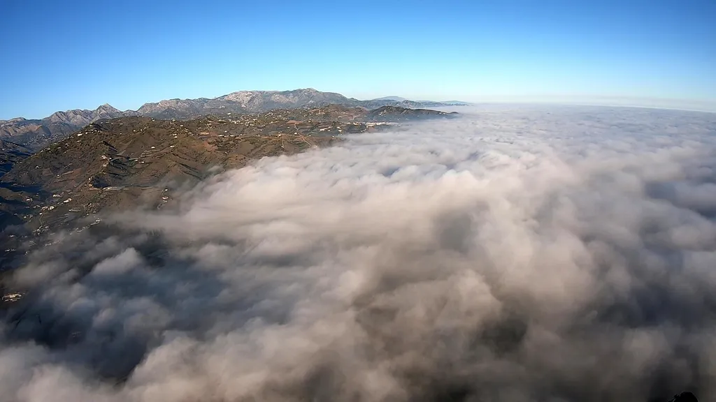Paisaje aéreo desde un paramotor volando por encima de un denso mar de nubes para conocer el paramotor precio.